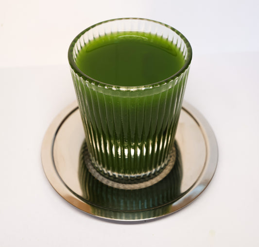 Verre strié rempli de matcha pur vert intense posé sur une soucoupe inox