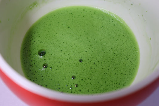 Matcha fouetté, vert vif et mousseux, dans un bol rouge